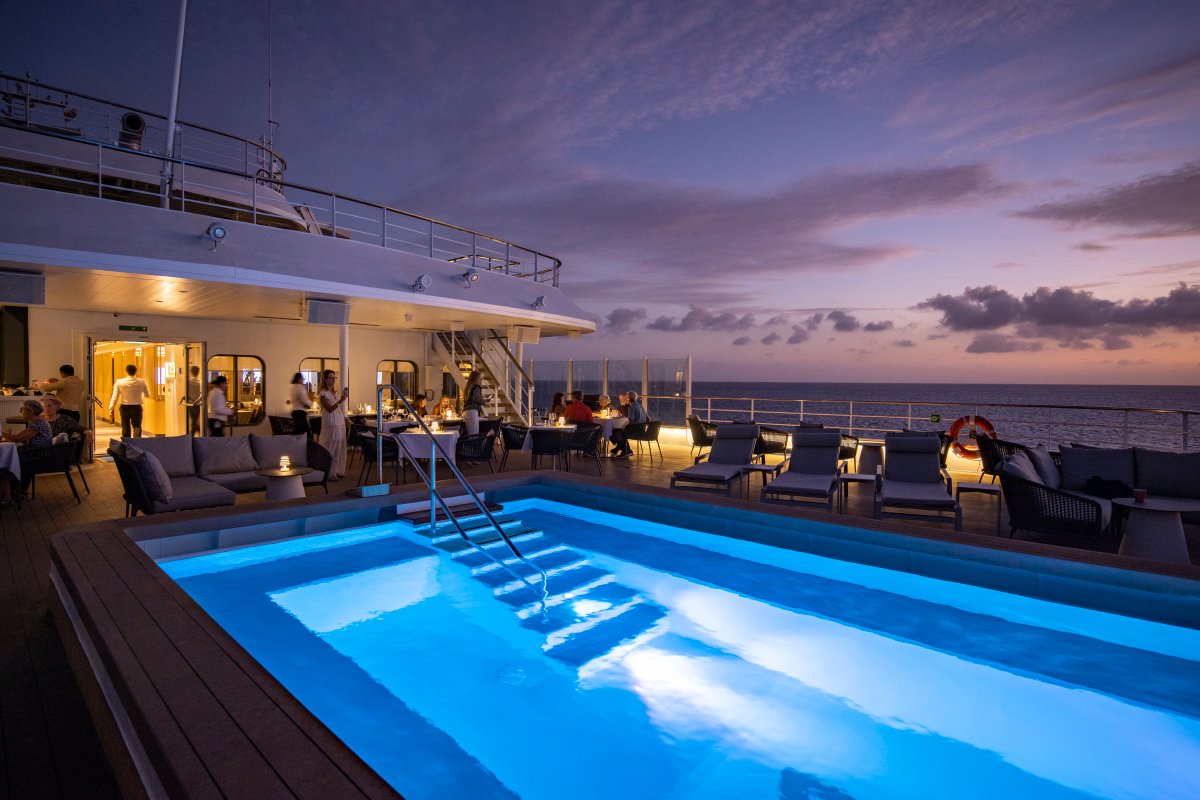 Deck com piscina iluminada do navio Swan Hellenic ao entardecer